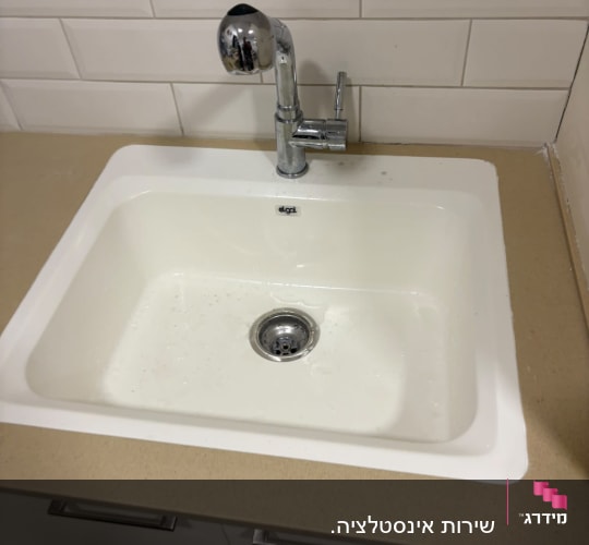 כיור מטבח לבן מותקן במשטח עם ברז כרום נשלף